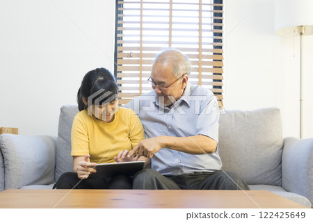 Old senior asian grandparent play and watch computer tablet with grandchildren girl at home. Bonding relationship in family.  122425649