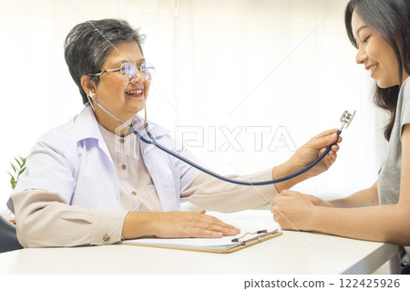 General practitioner taking notes when talking to female patient in hospital. General practitioner taking notes when talking to female patient in hospital. 122425926
