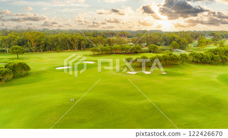 A stunning sunset view of a golf course with sand traps and vibrant greenery 122426670