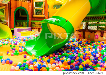 A colorful indoor playground with vibrant slides and a cheerful ball pit for kids. 122426671
