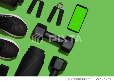 Flat lay Fitness Equipment. Mat, sneakers, expanders, dumbbells with smartphone on green background. Space for your text. Flat lay Fitness Equipment. Mat, sneakers, expanders, dumbbells with smartphone on green background. Space for your text. 122426764