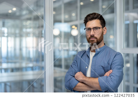 Portrait of confident serious man at workplace inside office. Businessman looking at camera with crossed arms, successful financier investor. Portrait of confident serious man at workplace inside office. Businessman looking at camera with crossed arms, successful financier investor. 122427035