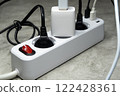 Plugs of household appliances and USB cables are fed into the power filter. Extension cord tee with three sockets and three USB ports for powering gadgets 122428361