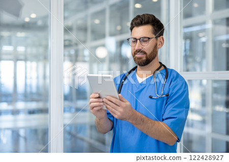 Doctor using tablet in hospital setting. Medical professional smiling while utilizing digital technology for healthcare. Stethoscope around neck symbolizes commitment to care. Doctor using tablet in hospital setting. Medical professional smiling while utilizing digital technology for healthcare. Stethoscope around neck symbolizes commitment to care. 122428927