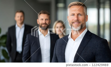 Confident executive leader standing in a relaxed pose with employees behind, modern office design, full body wide angle 122429469