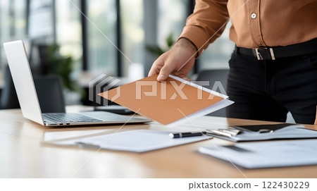 A new employee being shown around the office by a colleague during the onboarding process, with a laptop and documents on the desk 122430229