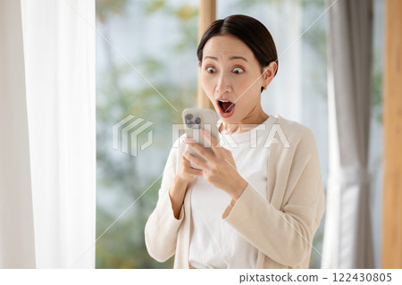 A woman surprised while looking at her smartphone A woman surprised while looking at her smartphone 122430805
