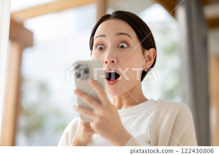A woman surprised while looking at her smartphone 122430806