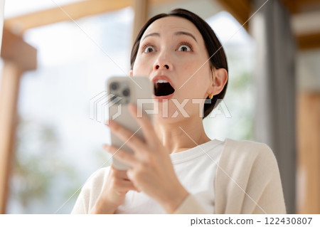 A woman surprised while looking at her smartphone 122430807