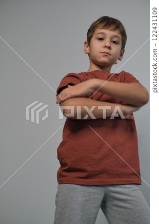 The boy's guarded posture and thoughtful gaze highlight self-reliance. This imagery resonates with the push for child advocacy. 122431109