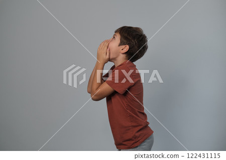 Boy in casual attire impersonates a wild creature, eyes popped and roaring. Reminds viewers of the uninhibited spirit of childhood and the universality of Youngster dramatizes a scare. 122431115