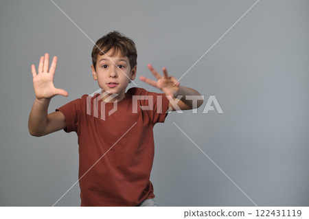 Boy in casual attire impersonates a wild creature, eyes popped and roaring. Reminds viewers of the uninhibited spirit of childhood and the universality of Youngster dramatizes a scare. 122431119