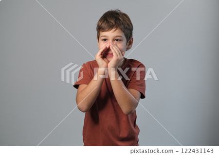 Young boy projects his voice, cupped hands around his mouth. This moment taps into the imaginative play of children's games and storytelling. Young boy projects his voice, cupped hands around his mouth. This moment taps into the imaginative play of children's games and storytelling. 122431143