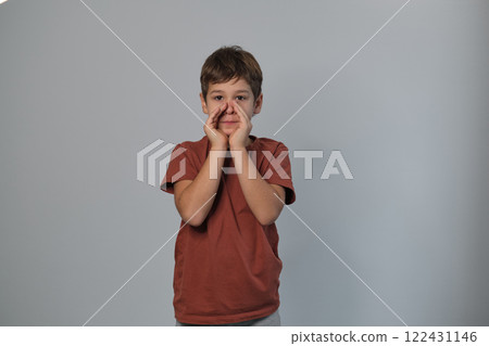 Joyful boy in a brick-red shirt calls out, hands cupped around his mouth. Captures the essence of youthful communication and vibrant play. Joyful boy in a brick-red shirt calls out, hands cupped around his mouth. Captures the essence of youthful communication and vibrant play. 122431146