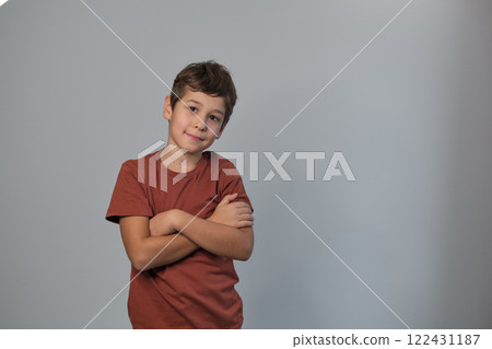 A boy stands with crossed arms, expression serious. His stance speaks to youth empowerment and the importance of listening to young voices. 122431187