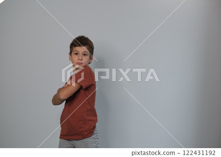 Arms crossed, a boy stands firm, showing determination. Reflects rising recognition of children's mental health awareness. 122431192