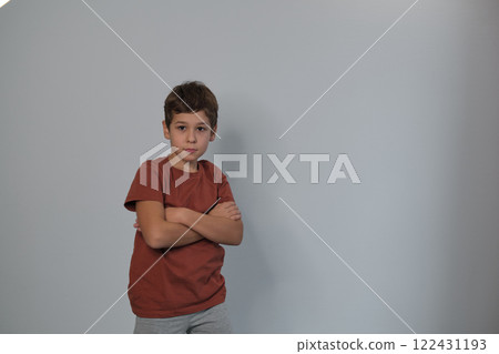 A stern-faced child with arms folded signifies resilience. Echoes the need for understanding youth challenges in society. 122431193