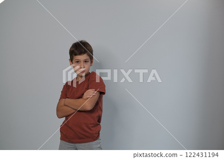 A boy stands with crossed arms, expression serious. His stance speaks to youth empowerment and the importance of listening to young voices. 122431194
