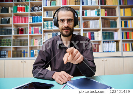 Webcam view young talking man making video call chat conference, in library Webcam view young talking man making video call chat conference, in library 122431429