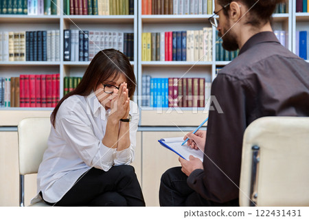 Mature serious sad woman at meeting in office of psychologist, social worker Mature serious sad woman at meeting in office of psychologist, social worker 122431431