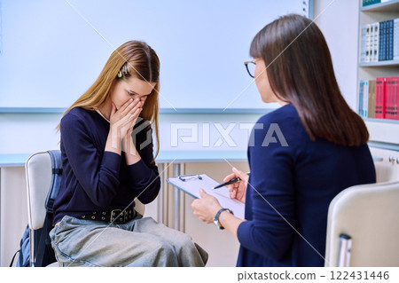 Sad serious teenage student girl talking with female school counselor, teacher 122431446