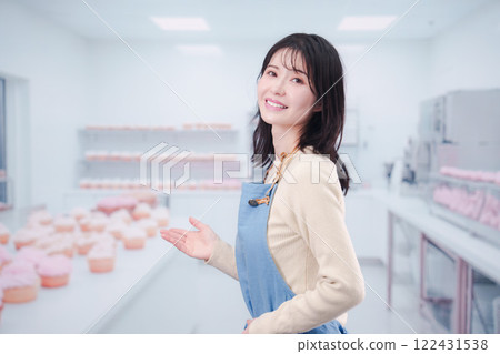 一位年輕的糕點師女人微笑著做糖果 122431538