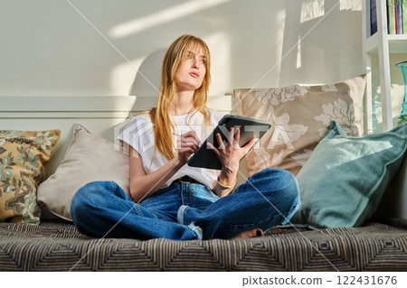 Portrait of female student on couch with digital tablet, studying at home Portrait of female student on couch with digital tablet, studying at home 122431676