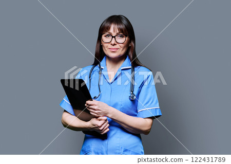 Portrait of female nurse with clipboards, on grey studio background Portrait of female nurse with clipboards, on grey studio background 122431789