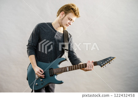 Young man playing electric guitar 122432458