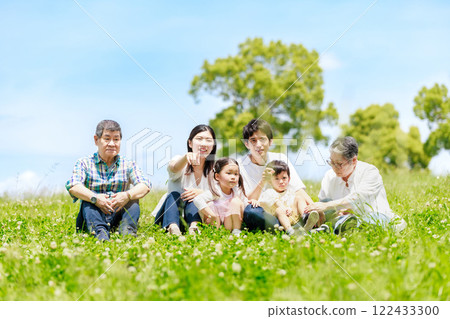 一家三代人坐在藍天下的草地上 一家三代人坐在藍天下的草地上 122433300