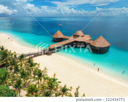 Aerial view of bungalow, white sandy beach, sea and green palms Aerial view of bungalow, white sandy beach, sea and green palms 122434771