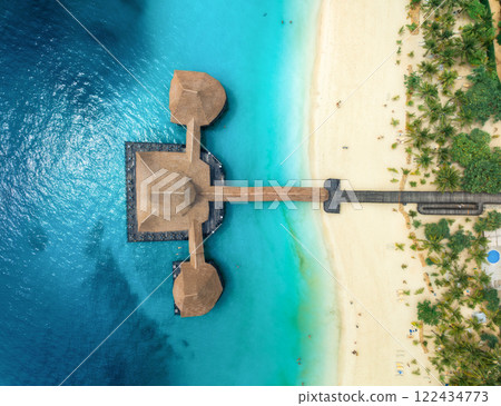 Aerial view of bungalow, white sandy beach, sea and green palms 122434773