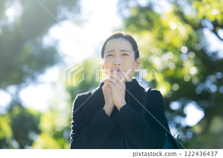 A woman in a coat walking on the sidewalk 122436437