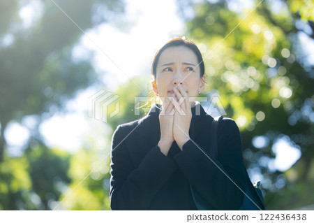 A woman in a coat walking on the sidewalk 122436438
