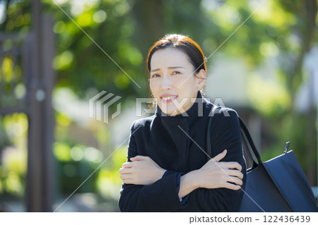 A woman in a coat walking on the sidewalk 122436439