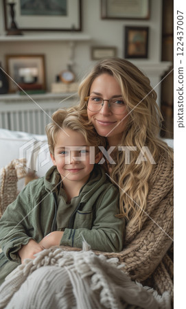 A woman and a young boy are sitting on a couch, with the woman wearing glasses A woman and a young boy are sitting on a couch, with the woman wearing glasses 122437007