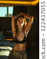 A woman is standing in a bedroom with her arms raised 122437055