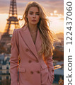 A woman wearing a pink coat stands in front of the Eiffel Tower 122437060