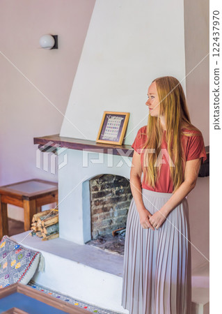 Woman by the fireplace during cozy winter evening. Warm and peaceful family moment indoors. Togetherness, love, and relaxation concept. A warm and inviting scene featuring a lit fireplace with glowing 122437970