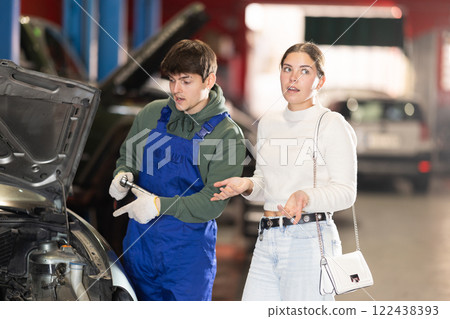 woman tells a mechanic about her car woman tells a mechanic about her car 122438393