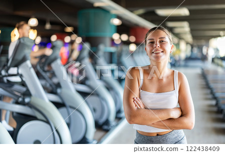 Young woman posing by exercise bike 122438409