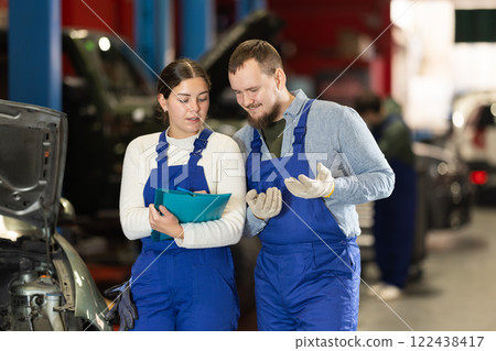 car service worker talks to a mechanic about car repairs 122438417