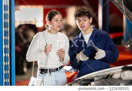 Mechanic checking young woman client car in car service center 122438503