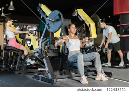 Athletic woman work out muscles of arms and hands on simulator in fitness club Athletic woman work out muscles of arms and hands on simulator in fitness club 122438551