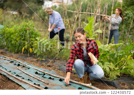 Girl is planting seeds in plastic bed 122438572