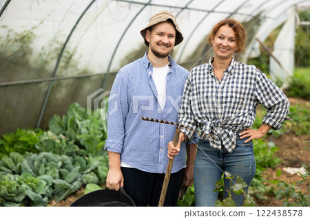 Farmer peasant woman and man works with garden plants in greenhouse Farmer peasant woman and man works with garden plants in greenhouse 122438578