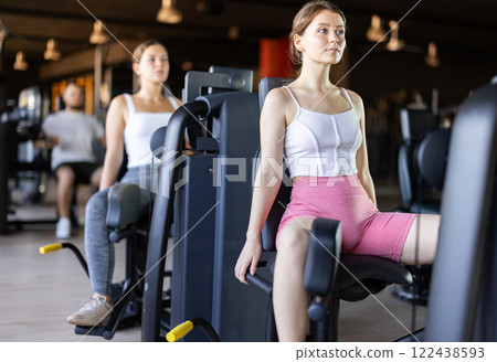 Young woman training her leg muscles on machine 122438593