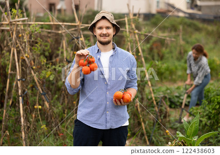 Portrait of happy male farmer picking red tomatoes Portrait of happy male farmer picking red tomatoes 122438603