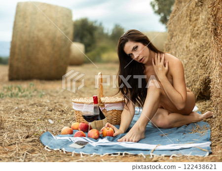 Nude woman sitting during picnic in field 122438621