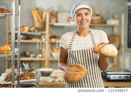Young woman are standing in kitchen with finished products two loaves of rye bread Young woman are standing in kitchen with finished products two loaves of rye bread 122438657